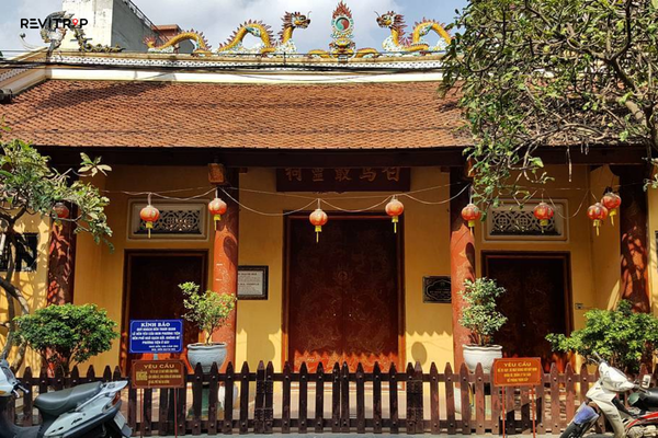 Front entrance of Bach Ma Temple with red lanterns and traditional architecture in Hanoi Old Quarter