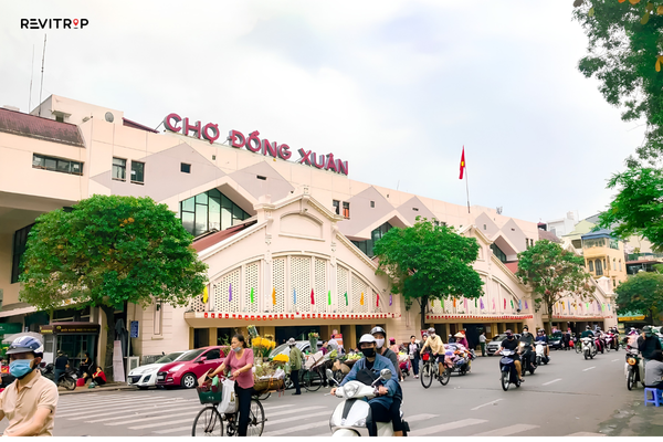 Dong Xuan Market exterior with motorbikes and pedestrians in Hanoi Old Quarter