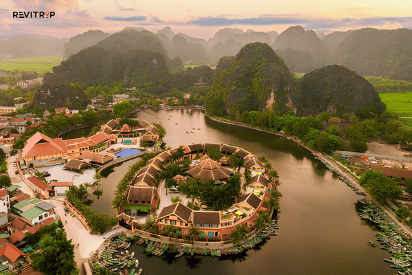 Aerial view of Aravinda Resort Ninh Binh beside a river and limestone mountains