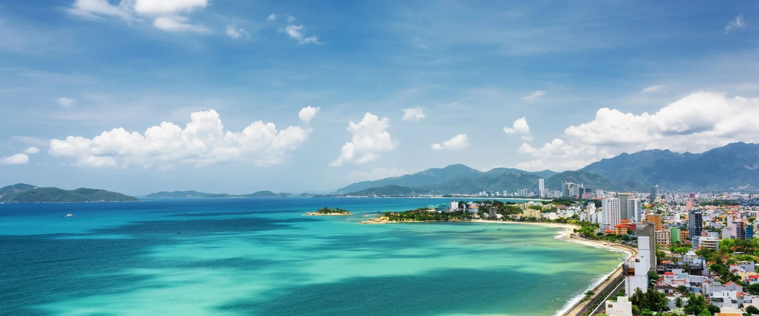 Nha Trang beach with turquoise sea, city skyline and mountains along Vietnam’s coast